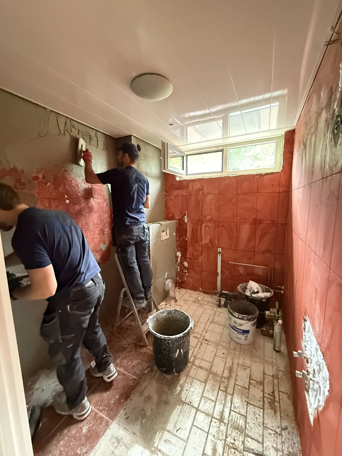 Twee vakmannen aan het werk in een badkamer